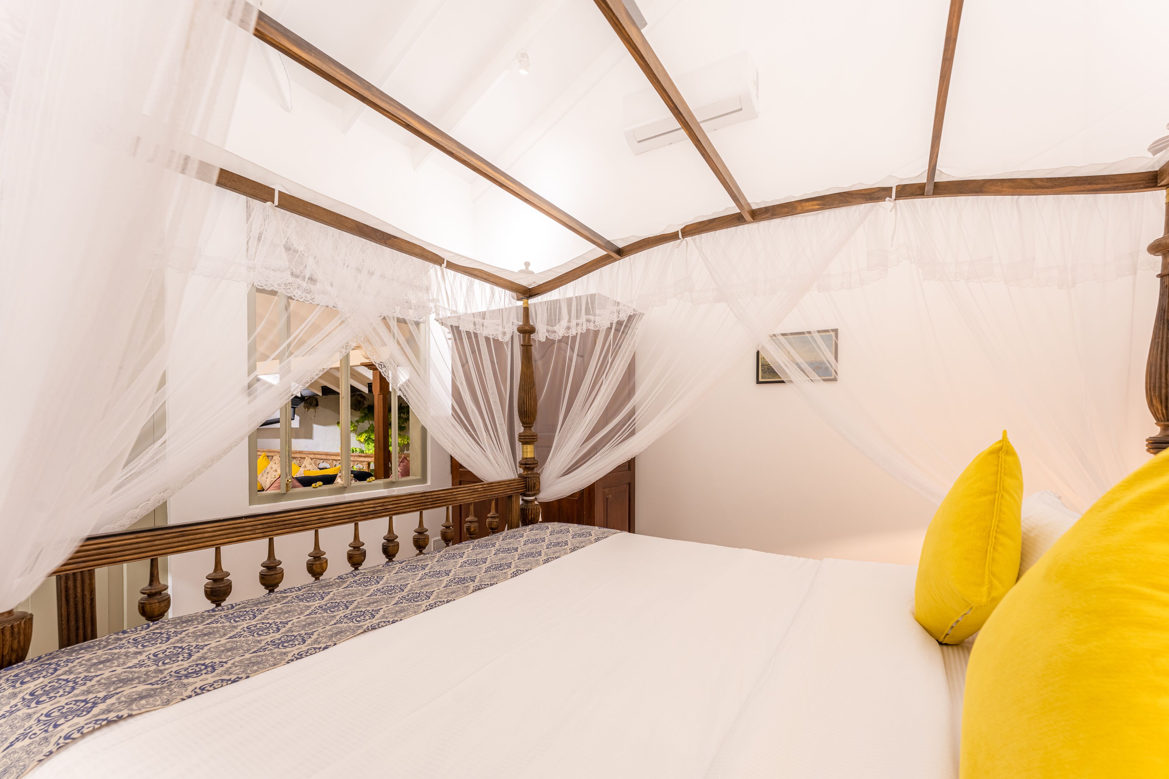 Un dormitorio con cama a dosel, cabecera de madera y edredón estampado.