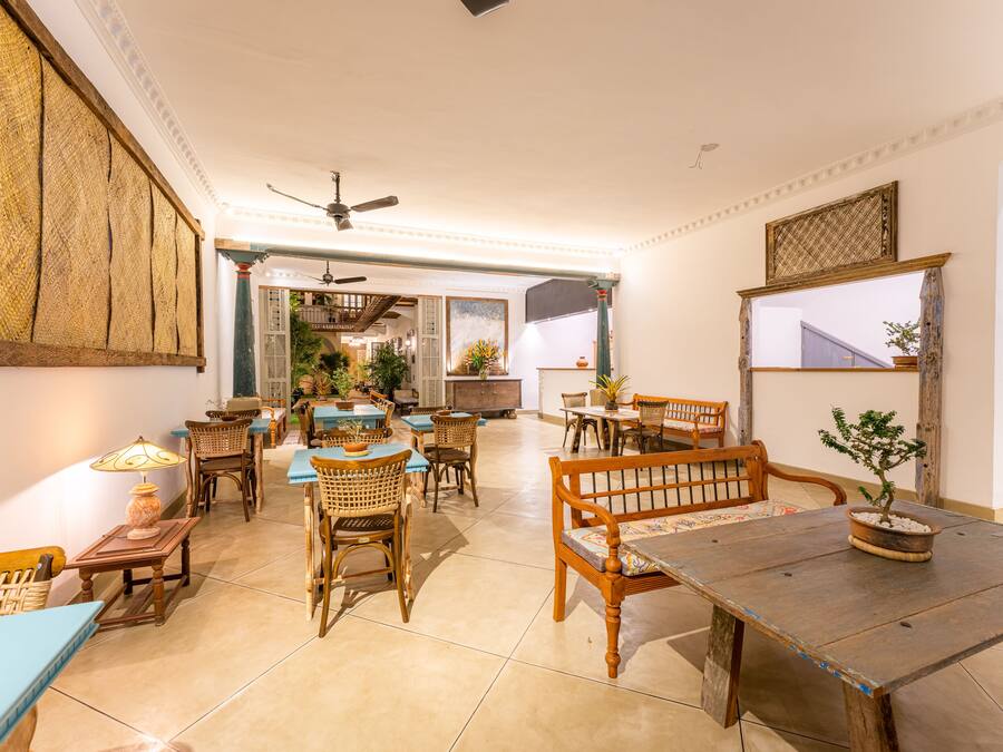 A spacious dining area with multiple tables and chairs, a ceiling fan, and a potted plant.