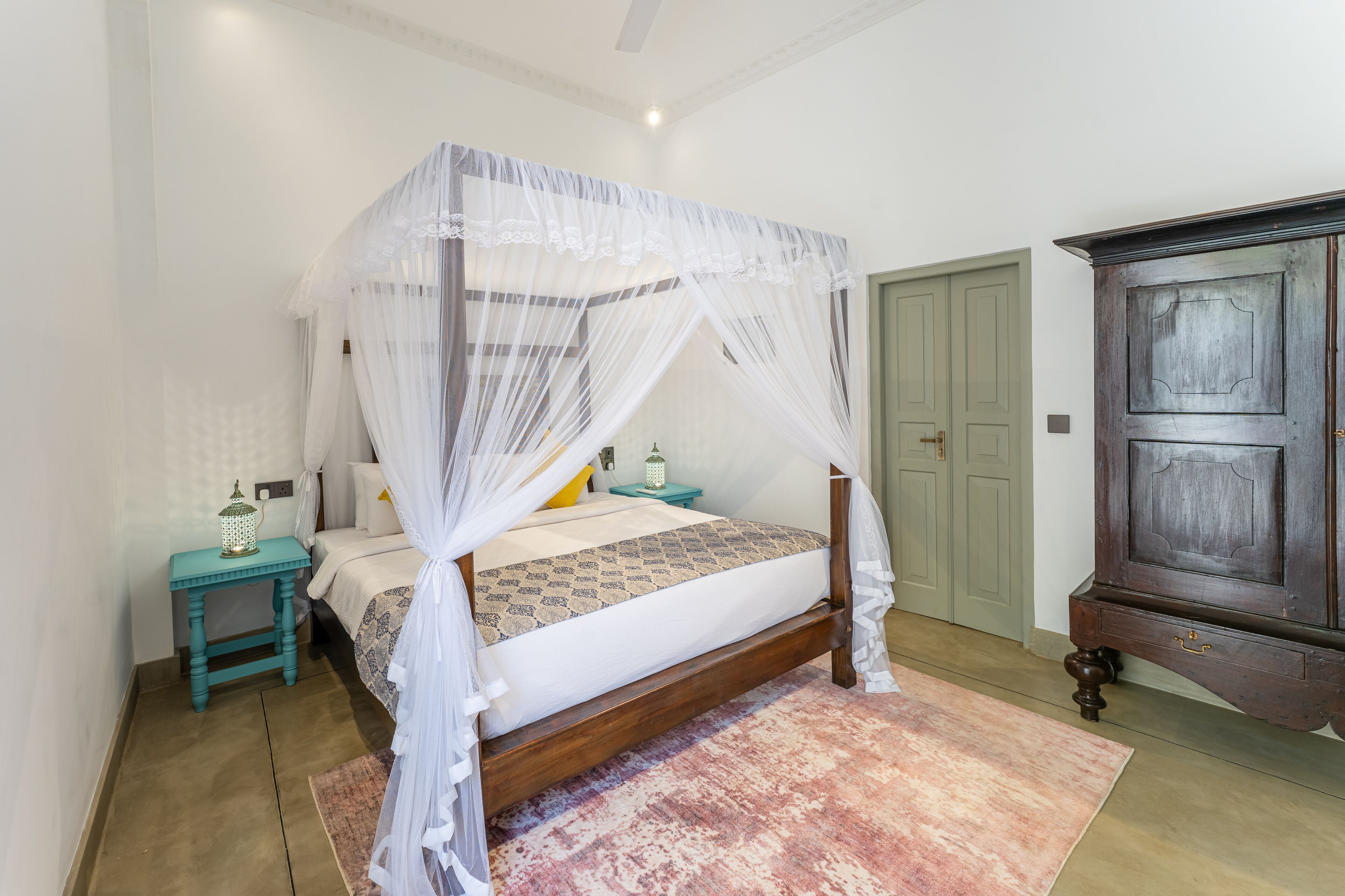 Une chambre à coucher avec un lit à baldaquin, une table de chevet, une commode et une porte.