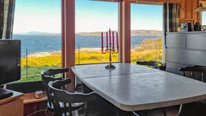 A dining area with a table and chairs, a candelabra, and a view of the sea through large windows. - Amazing home in Rennesøy with house sea view (Rennesøy)