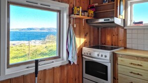 A kitchen with a view of the sea, a stove, and wooden cabinetry. - Amazing home in Rennesøy with house sea view (Rennesøy)
