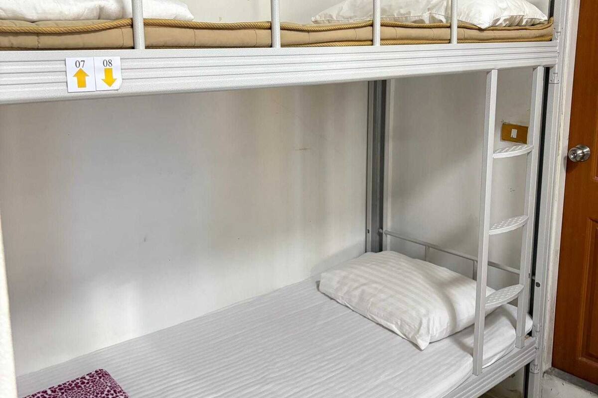 A bunk bed with two levels, a white door, and a shelf unit.