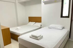 A hotel room with two single beds, each with a wooden headboard and white bedding. - OYO 75577 Palace Hostel (Bangkok)