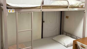A bunk bed room with a desk and chair, a door, and a small shelf with a towel.