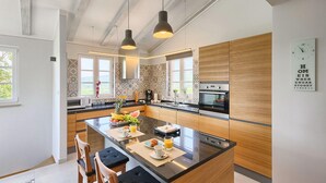 Una cucina moderna con isola centrale, mobili in legno e illuminazione a sospensione.