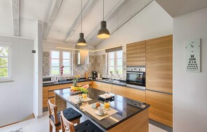 A modern kitchen with a central island, wooden cabinetry, and pendant lighting. - Awesome home in Podpican (Podpican)
