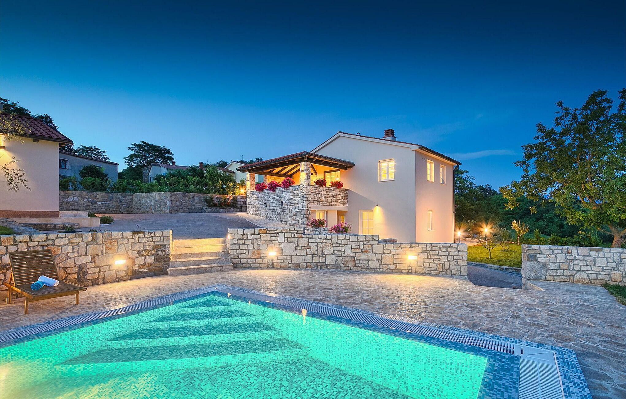 Una casa moderna con piscina in pietra e un muro in pietra.