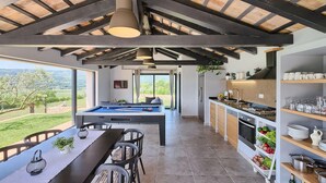 A modern kitchen with a built-in stove, a dining area with a pool table, and a view of the countryside. - Awesome home in Podpican (Podpican)