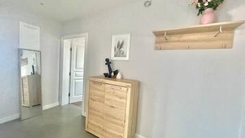 A hallway with a wooden cabinet, a wooden shelf with a vase, and a framed picture on the wall.