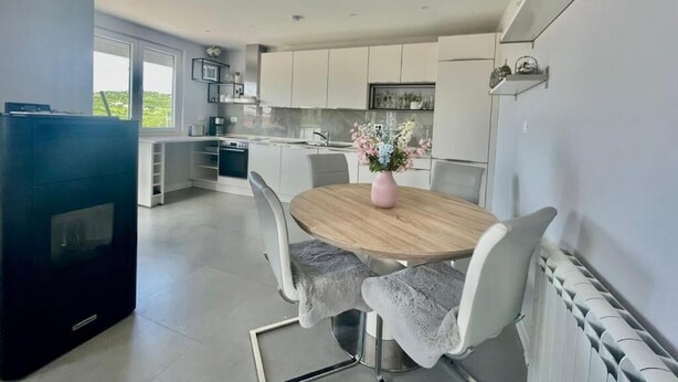 Una cocina moderna con armarios blancos, una mesa de comedor con sillas y una estufa integrada.