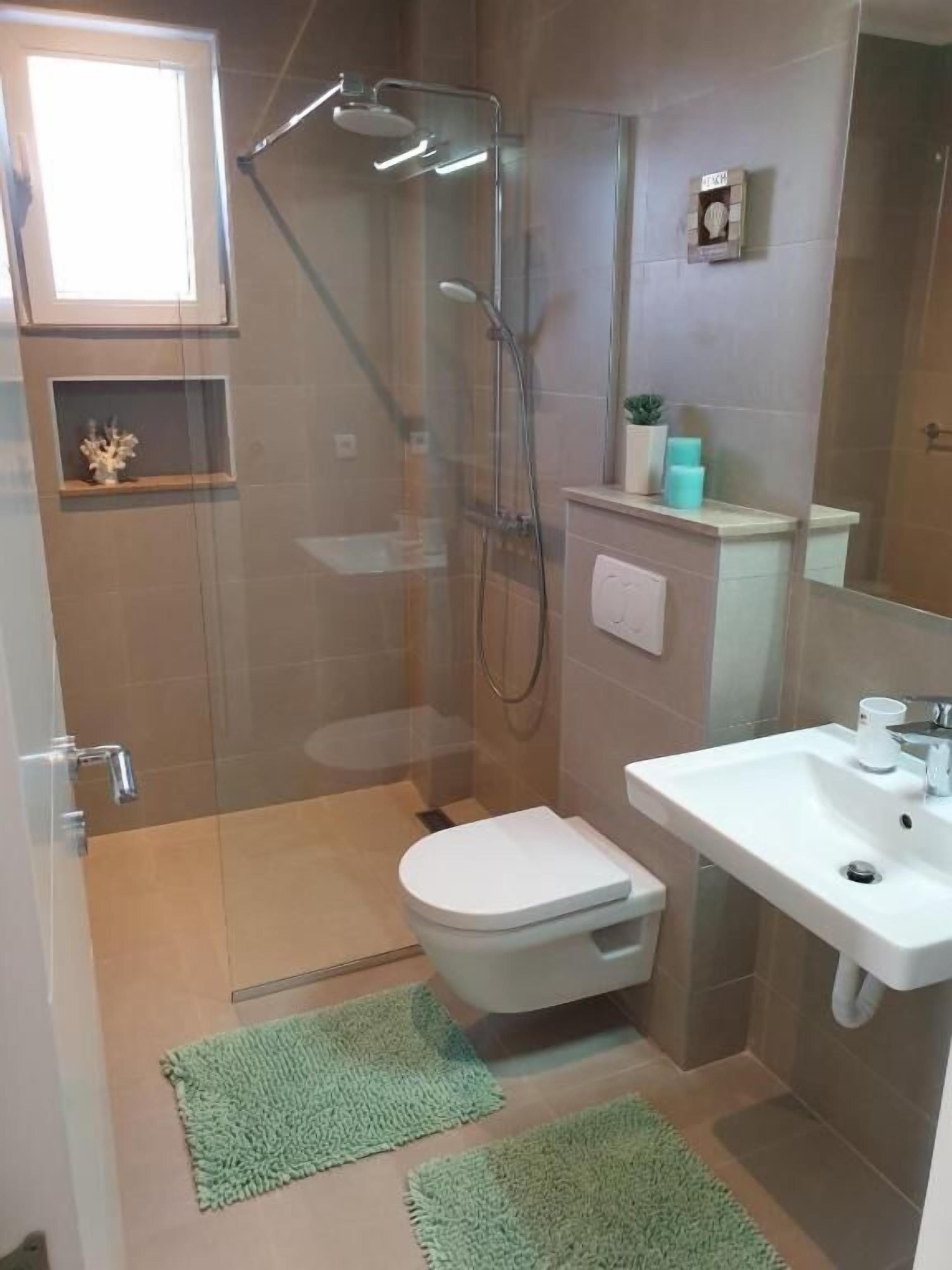 A modern bathroom with a glass-enclosed shower, a white sink, and a toilet.
