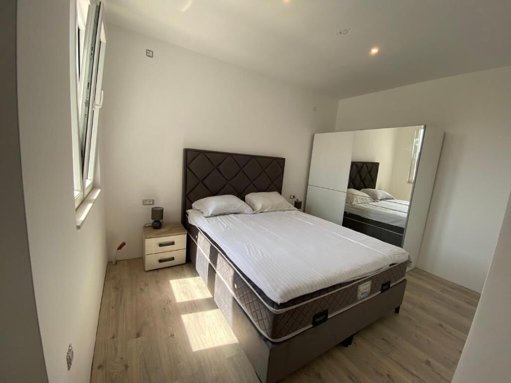 Un dormitorio con cama, mesita de noche, cómoda, espejo y armario.