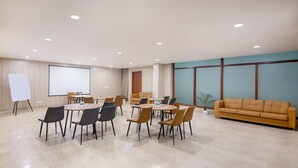 A conference room with round tables, chairs, a whiteboard, and a large screen. - Treebo FlxHo Trio, Medanta Medicity Gurgaon (Gurugram)