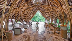 An arched bamboo structure with seating and a stone floor.