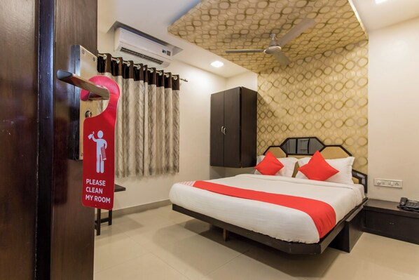 A hotel room with a bed, a wardrobe, a hanging coat rack, and a sign requesting room cleaning.