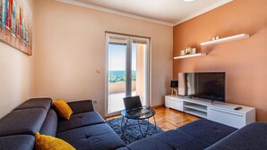 Una sala de estar moderna con un conjunto de sofá, un televisor y un balcón con vistas.