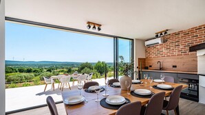 Un comedor con vistas al campo, una pared de ladrillo y una cocina moderna.