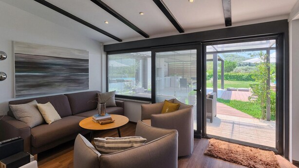 A modern living room with a sofa, armchairs, a coffee table, and a large window with blinds. - Amazing home in Rovinj (Rovinj)