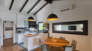 A modern kitchen with a central island, pendant lighting, and a dining area with a round table and chairs. - Amazing home in Rovinj (Rovinj)