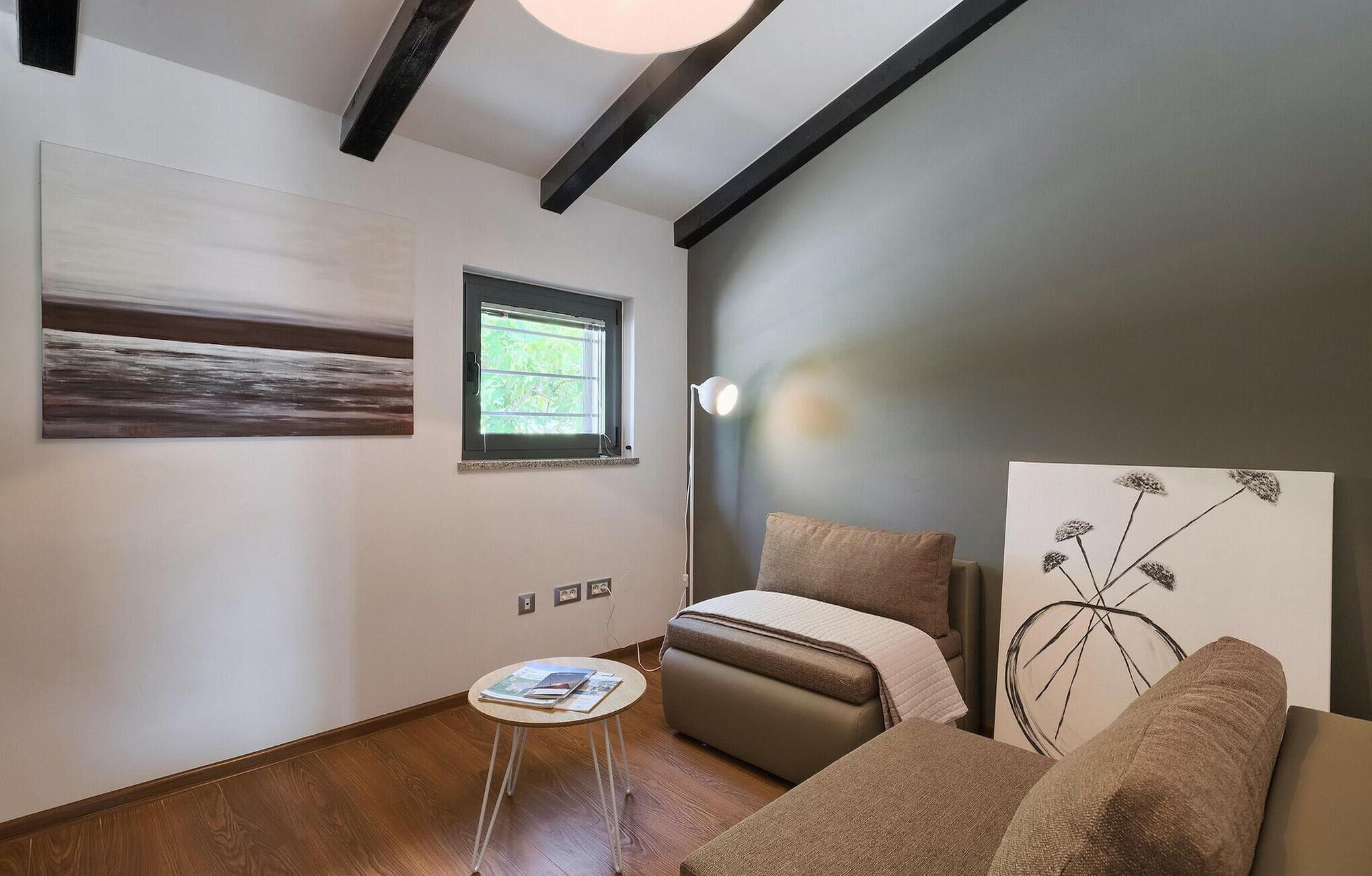 A modern living room with a sofa, a small table, a window, and artwork on the walls.