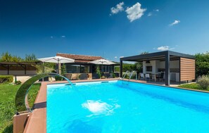 A modern outdoor pool area with a clear blue pool, a covered seating area, and a separate dining space. - Amazing home in Rovinj (Rovinj)