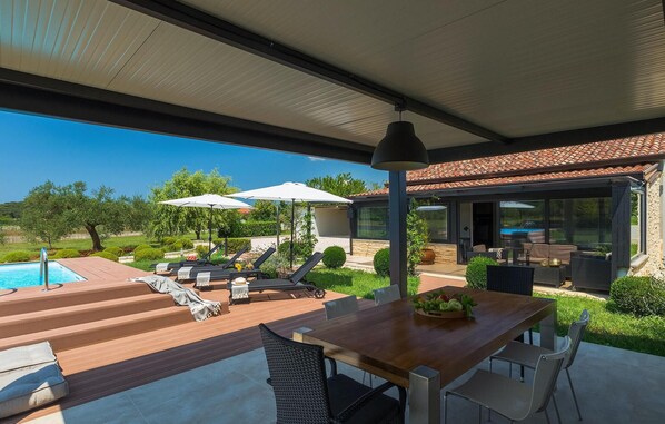 A covered outdoor area with a pool, lounge chairs, and a dining table. - Amazing home in Rovinj (Rovinj)
