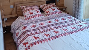 Puupaneloitu makuuhuone, jossa on sängyllä kuviollinen päiväpeite ja sitä vastaavat koristetyynyt.