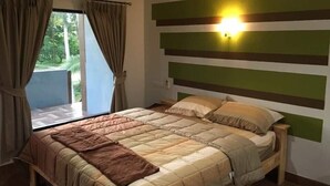 Un dormitorio con una cama, cortinas, un ventanal y una pared a rayas horizontales.