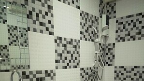 Un baño con lavamanos, inodoro y ducha blancos. Las paredes están cubiertas de un patrón de baldosas a cuadros blanco y negro.