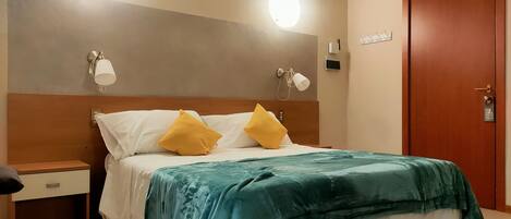 A hotel room with a bed, nightstand, and a door.