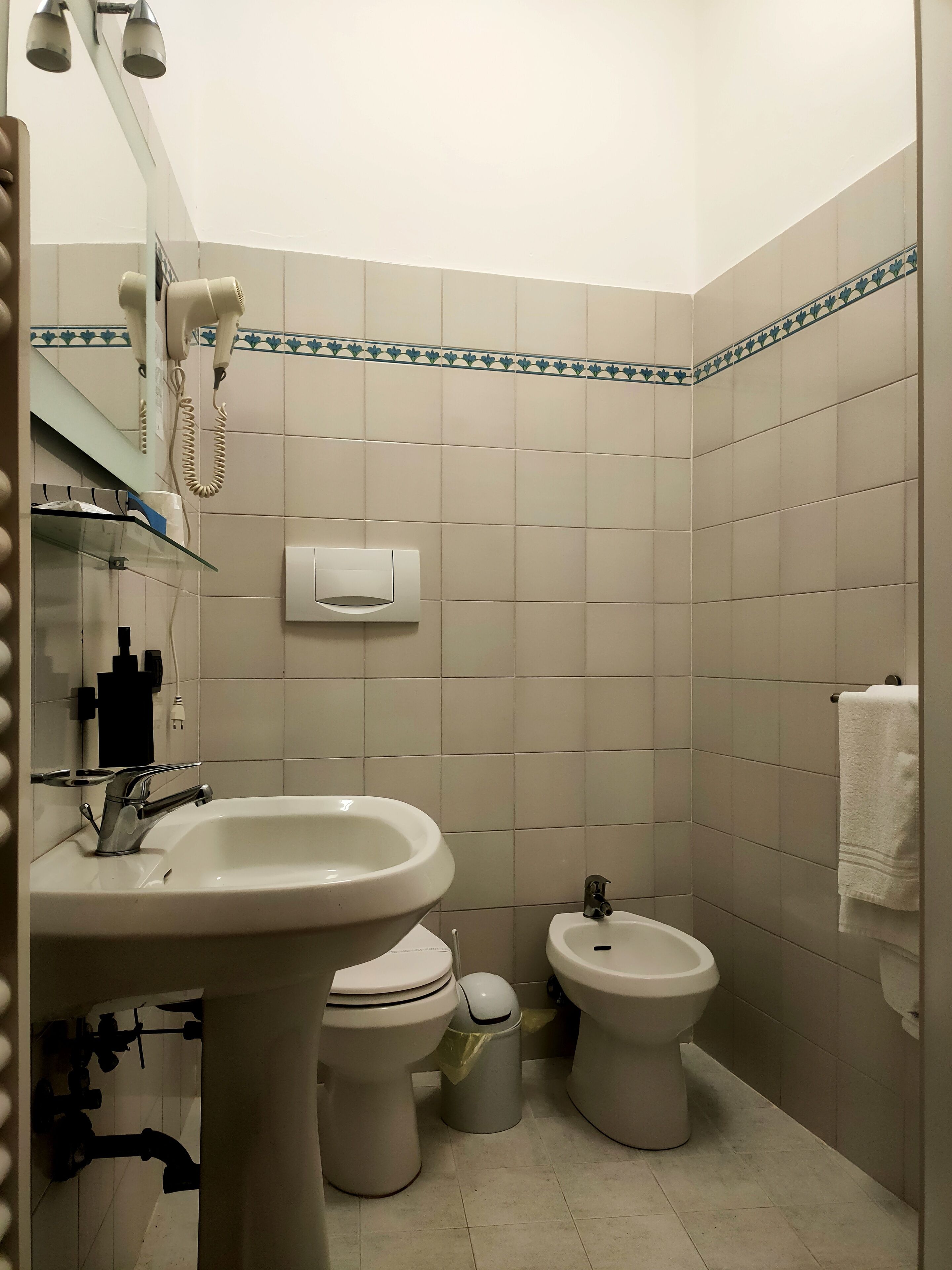 Une salle de bain équipée d’un lavabo, de deux toilettes, d’un miroir et d’un porte-serviettes.