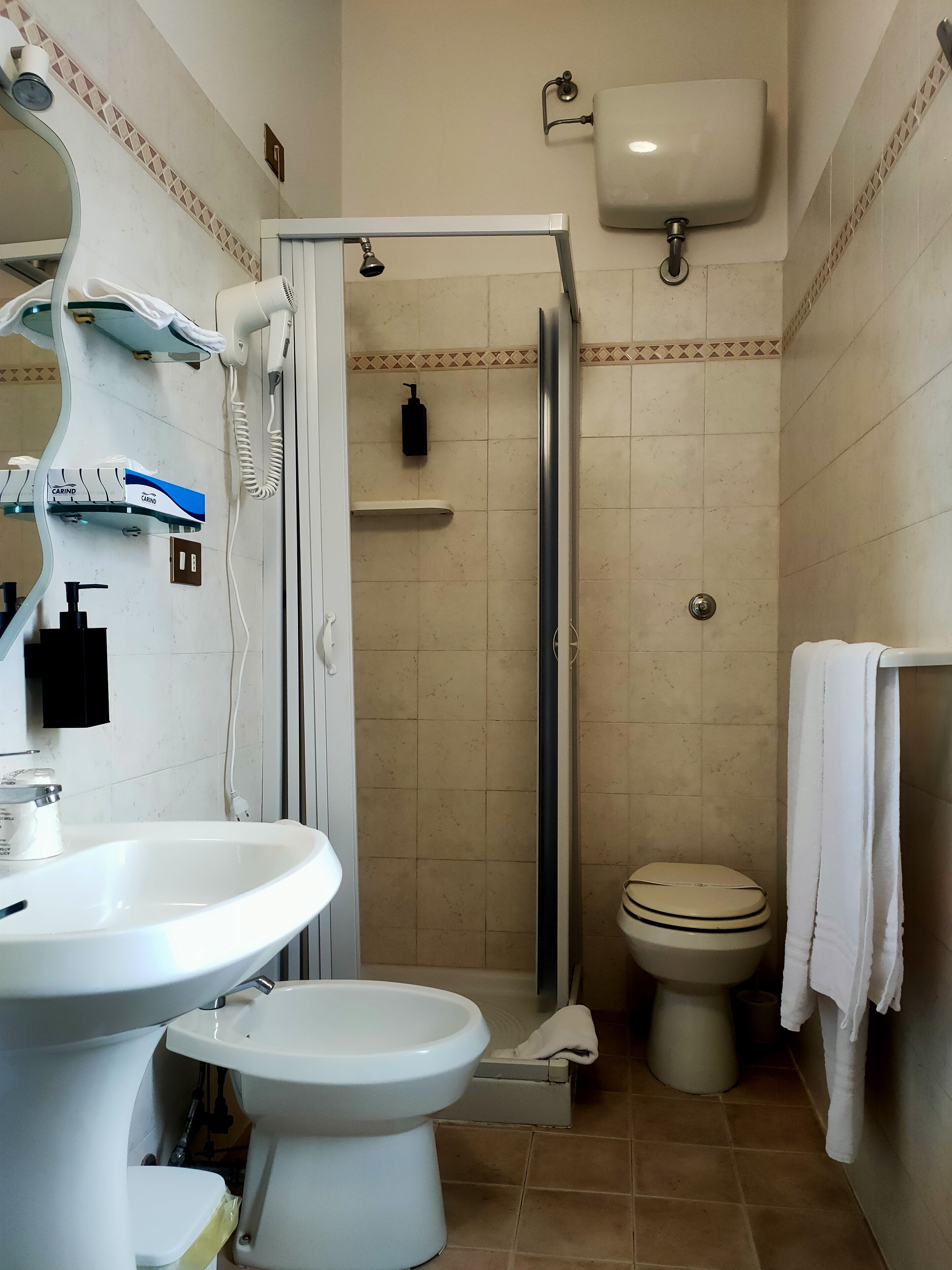 A bathroom with a white sink, toilet, and shower area.