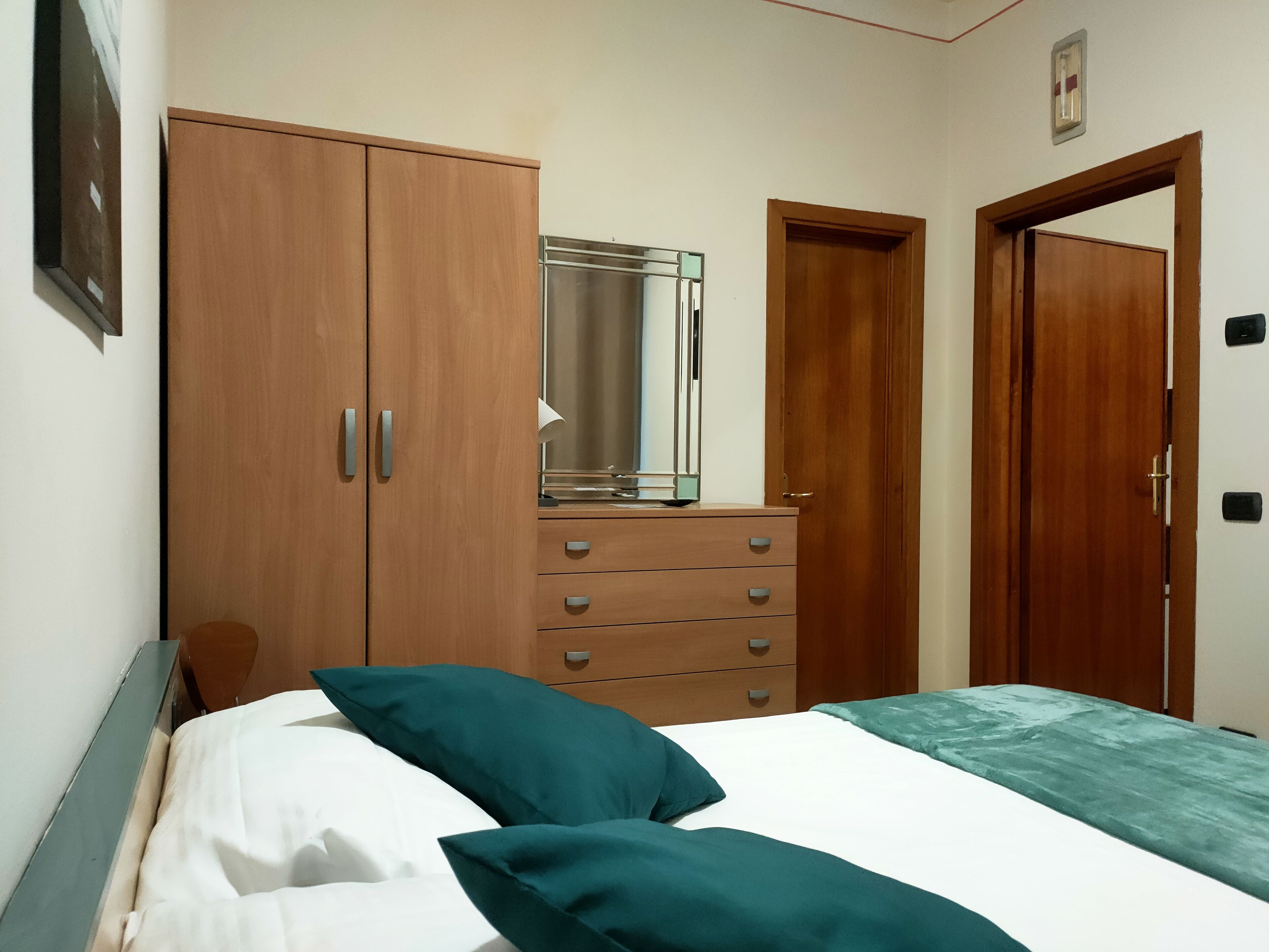 Ein Schlafzimmer mit einem Bett, einem Schminktisch, einem Spiegel und zwei Türen.