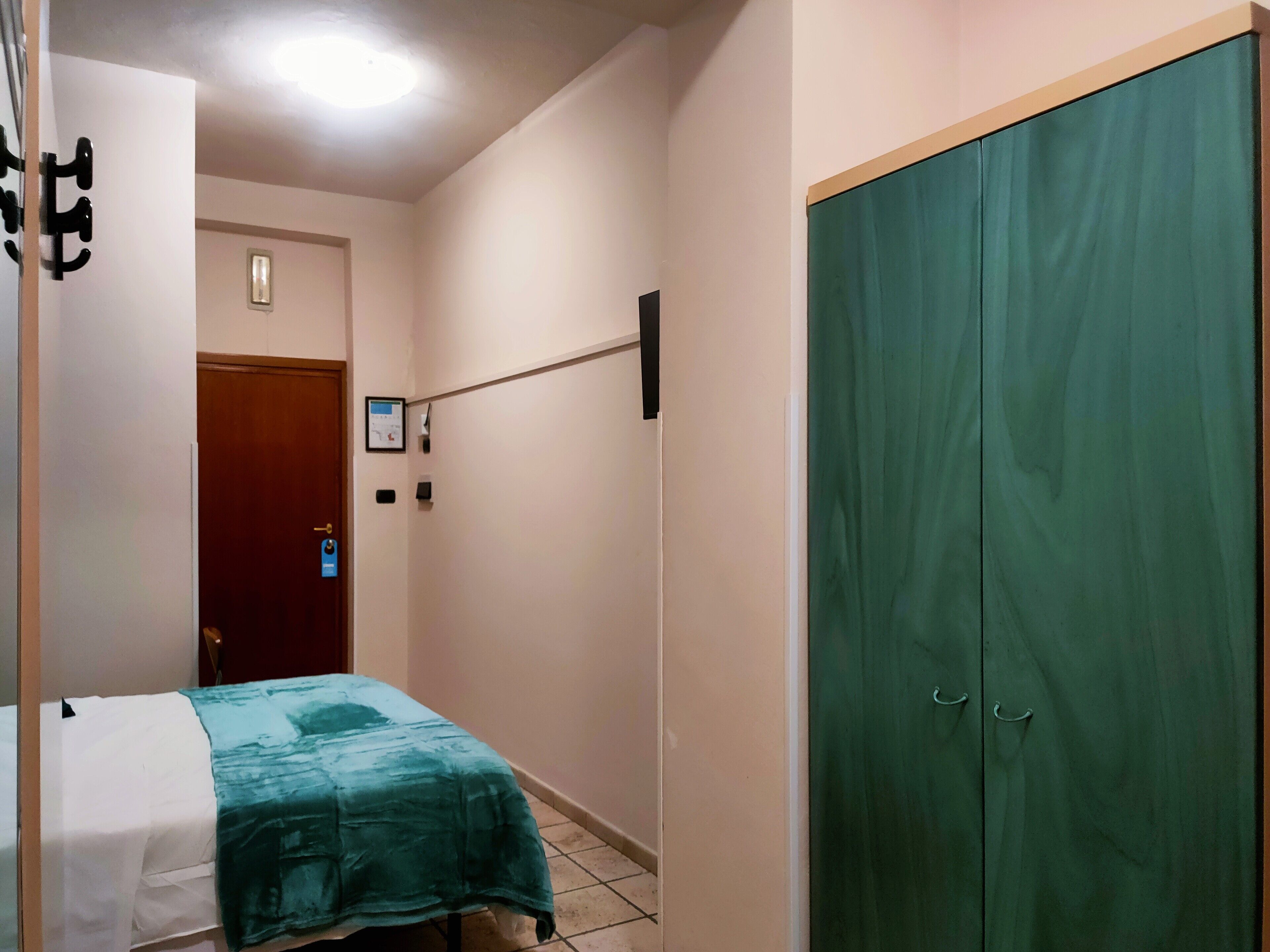 Un dormitorio con cama, armario y puerta con interruptor de luz.