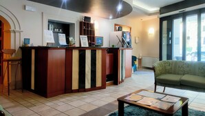 Un área de recepción con mostrador, sofá, mesa de centro y un ventanal grande.