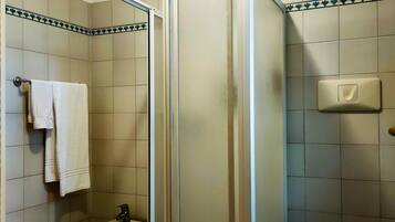 Un baño con cabina de ducha, un bidé, un inodoro y un perchero para toallas.