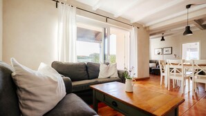 A living room with a sofa, a wooden coffee table, and a dining area with chairs and a table. - Awesome home in Pula with sauna (Pula)