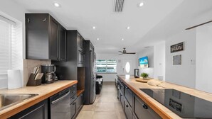 A modern kitchen with dark cabinets, stainless steel appliances, and a wooden countertop. - Biscayne Shore-Stylish 3BR Tropical Family Retreat (Miami)