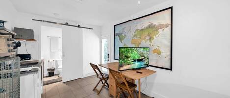 A modern, minimalistic room with a wooden desk, a large world map, and a computer monitor displaying a nature scene.