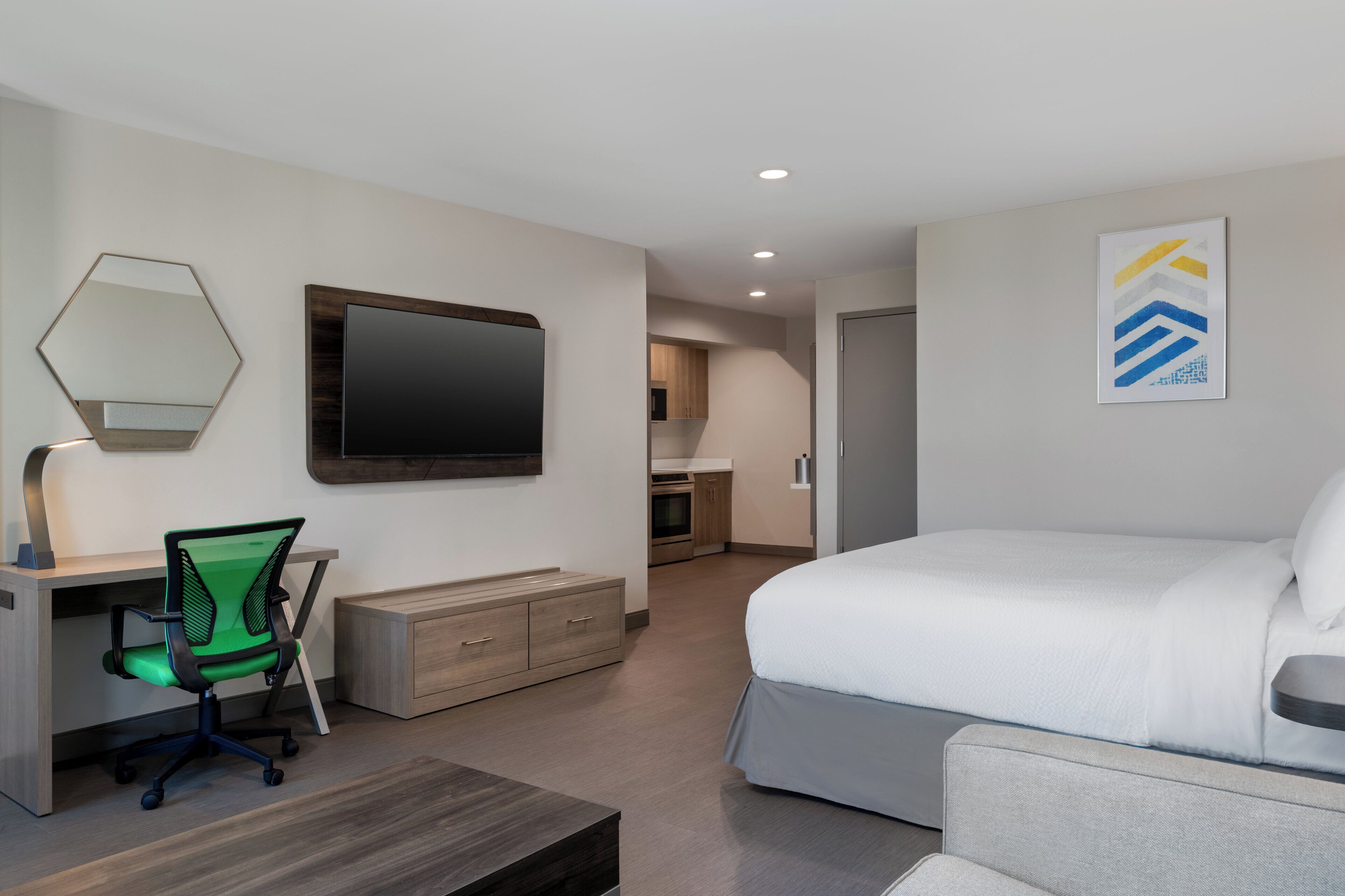 Una habitación de hotel moderna con cama, escritorio, silla y televisor.