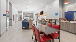 A modern hotel lobby with a central seating area, a kitchen counter, and a reception desk. - Holiday Inn Express & Suites Bronx - Barnabas area by IHG (Bronx)