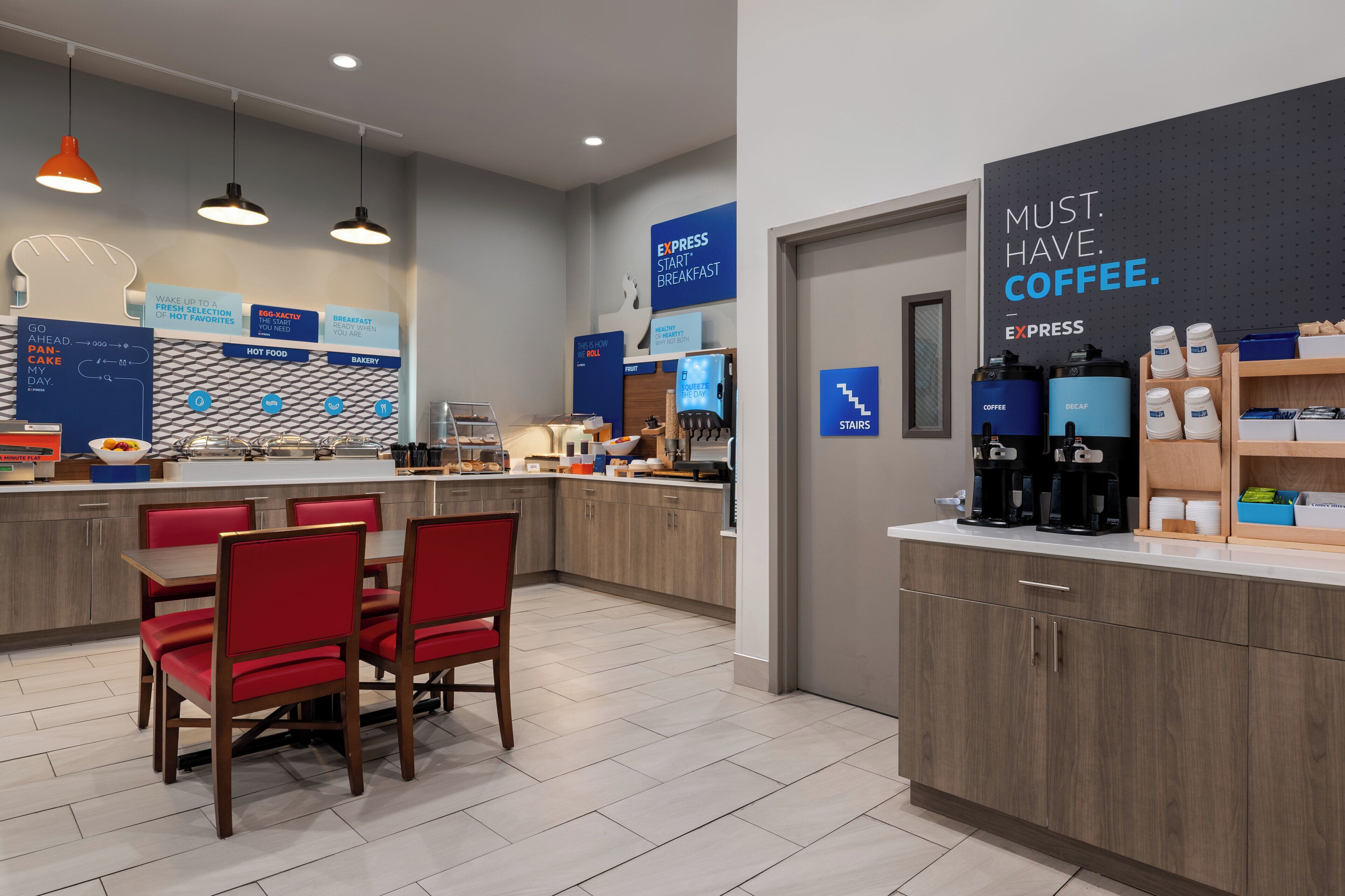 A modern breakfast area with a counter, seating, and coffee machines.