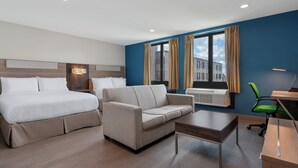 A modern hotel room with a bed, sofa, desk, and chair. - Holiday Inn Express & Suites Bronx - Barnabas area by IHG (Bronx)