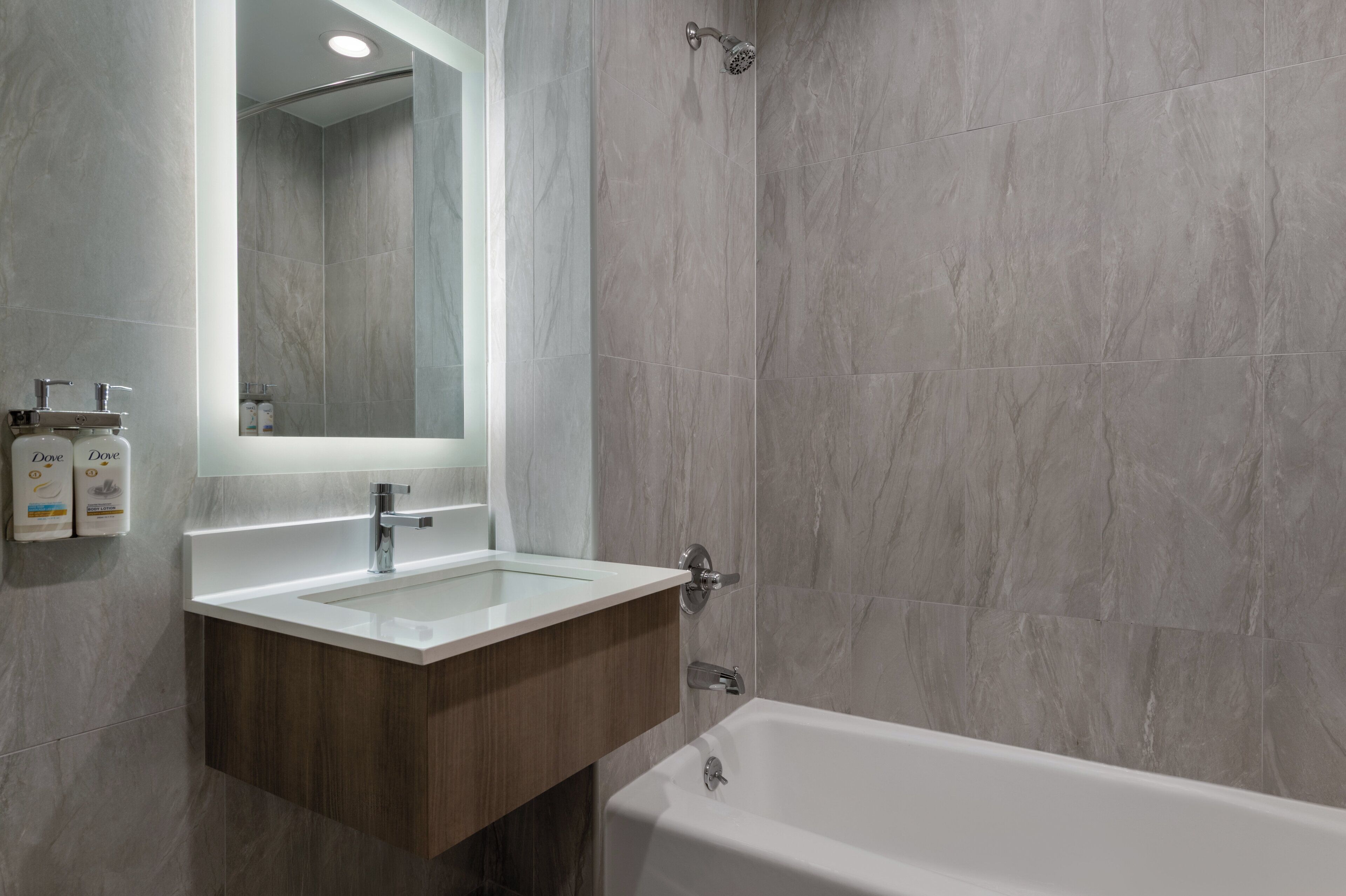 A modern bathroom with a white sink, wooden vanity, and a bathtub.