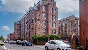 A large brick building with multiple windows and a clock on the facade. - Stylish 1-bed Studio - Heart of Nottingham (Nottingham)