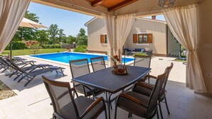An outdoor patio with a pool, covered seating, and a table with chairs. - Lovely home in Svetvincenat (Svetvincenat)