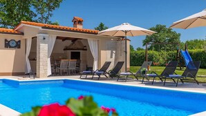 A pool area with lounge chairs, umbrellas, and a covered seating area. - Lovely home in Svetvincenat (Svetvincenat)