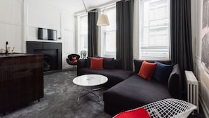 A modern living room with a black sofa, a round white coffee table, and a TV mounted on the wall.