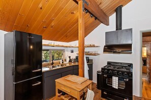 Una cocina moderna con un refrigerador negro, un banco de madera y una estufa clásica.