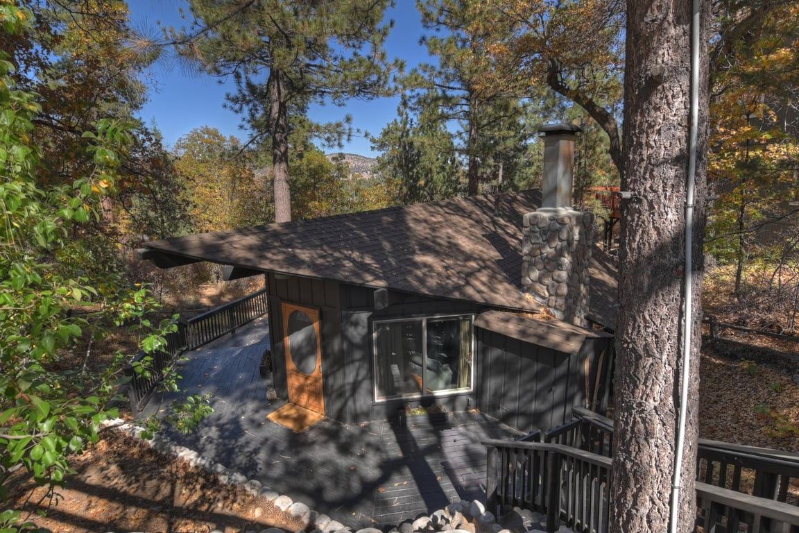 Une cabane dotée d’une terrasse en bois, d’un mur en pierre et d’une rambarde en métal.